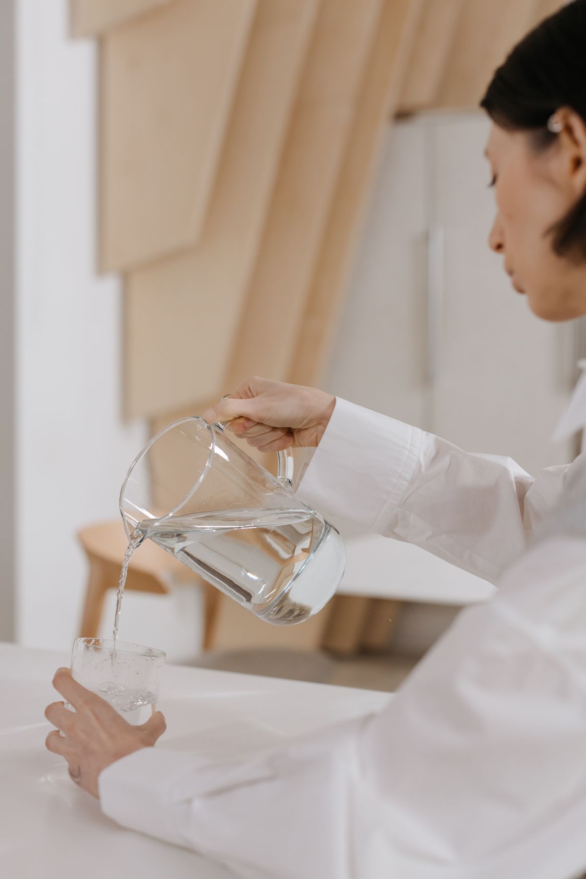 A woman pouring clean, treated water from a pitcher in a Jacksonville home